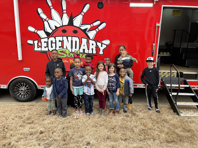 Real kids posing in front of the Legendary Strikes mobile bowling truck and game truck